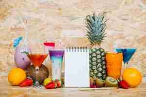 Free photo cocktail and tropical fruits with blank notepad