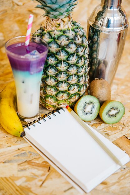 Cocktail and tropical fruits with notepad