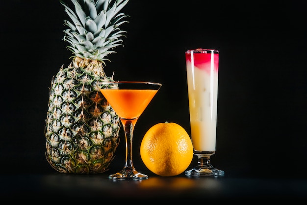 Cocktails and exotic fruits on black background