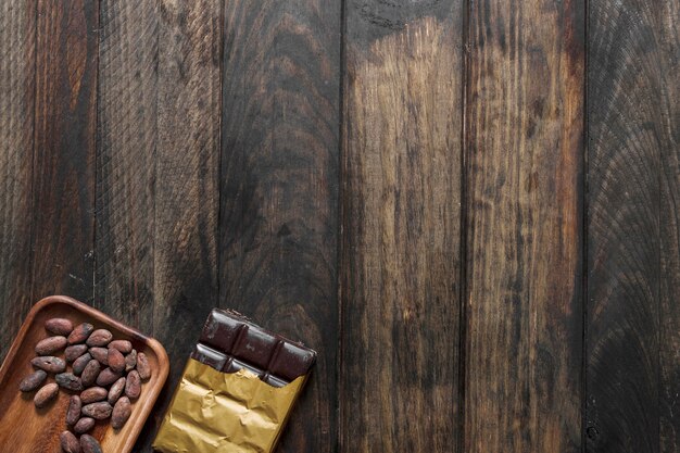 Cocoa beans and chocolate bar on wooden background