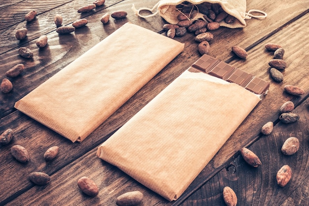 Le fave di cacao si sono sparse intorno alle barre di cioccolato sulla tabella di legno