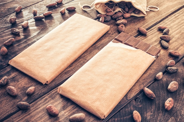 Cocoa beans spread around the chocolate bars on wooden table