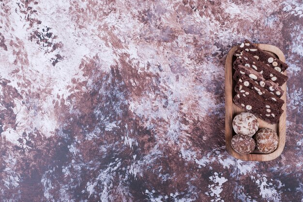 Cocoa cake slices and gingerbreads on a wooden platter.