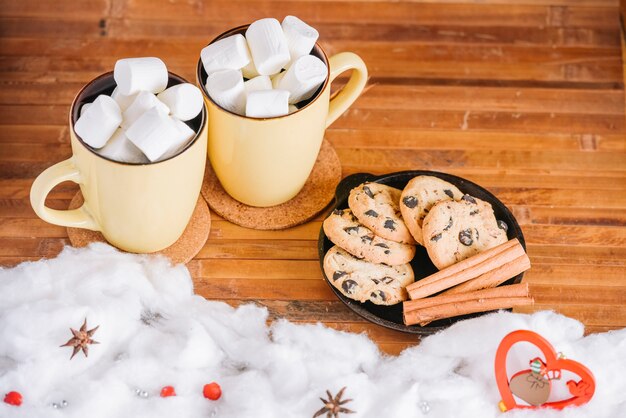 Cocoa cups with marshmallows and plate with cookies