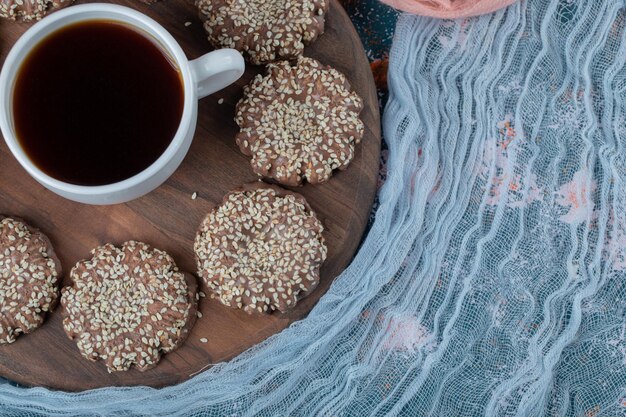 Cocoa sesame cookies on rustic wooden board with a cup of tea.