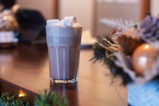 Cocoa with marshmallows in a transparent glass in a coffee shop on the background of new year's decoration.