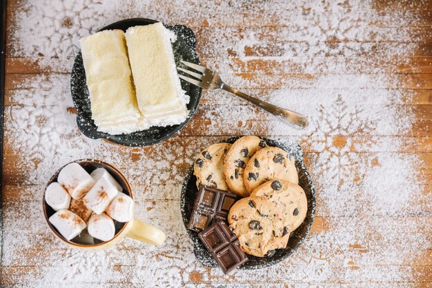 Free photo cocoa with sweets on powdered sugar decorated table