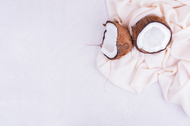 Free photo coconut broken into two pieces on beige tablecloth