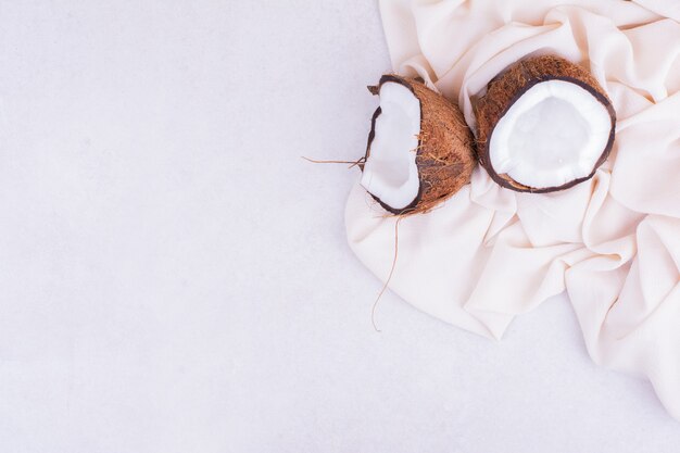 베이지 색 식탁보에 두 조각으로 깨진 코코넛