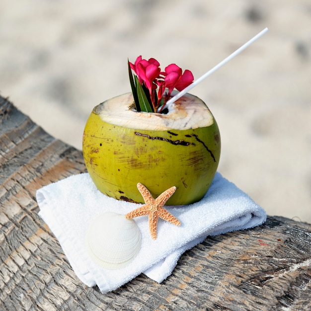 Cocktail di cocco con cannuccia su una palma in spiaggia