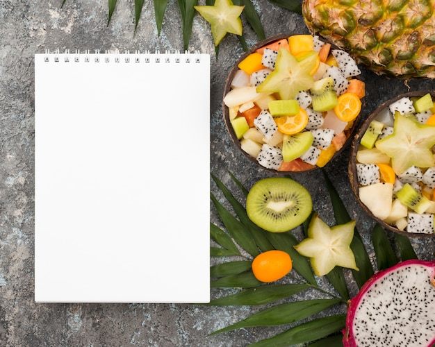 Coconut filled with fruit salad and empty notepad