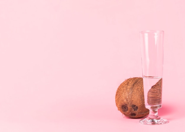 Coconut and glass of water on pink background