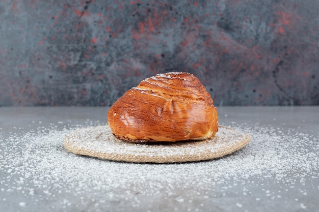 Free photo coconut powder covered trivet under a sweet bun on marble surface