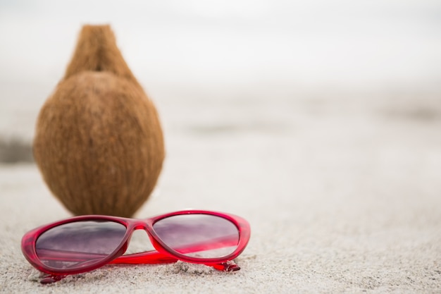 Coconut and a sunglass kept on the sand