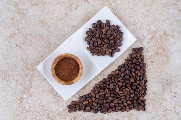 Coffee bean piles and a small bowl of ground coffee 