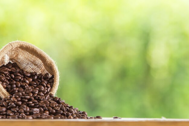 木製の卓上に灰色の背景をぼかして茶色のコーヒー豆