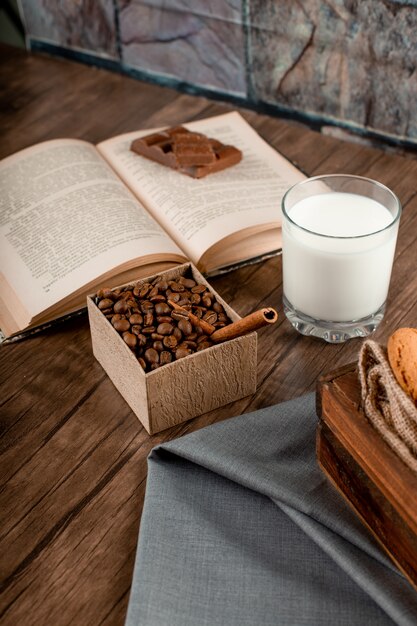 Бесплатное фото Кофе в зернах, стакан молока и книга