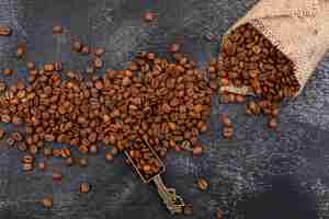 Free photo coffee beans beans in metal spoon and sackcloth on dark surface