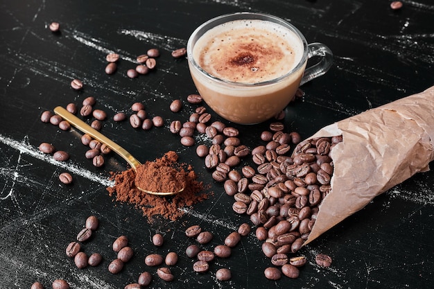 Coffee beans on black background with a cup of drink.