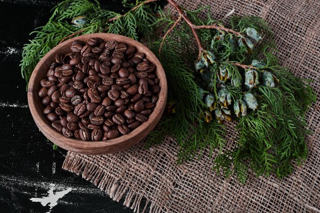 Coffee beans on black background in the wooden cup.