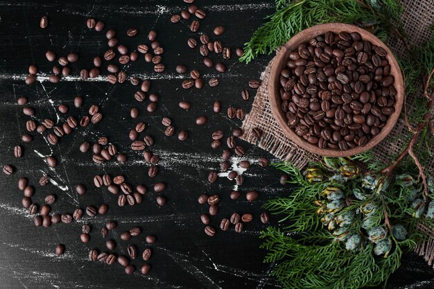 Coffee beans on black background in the wooden cup.