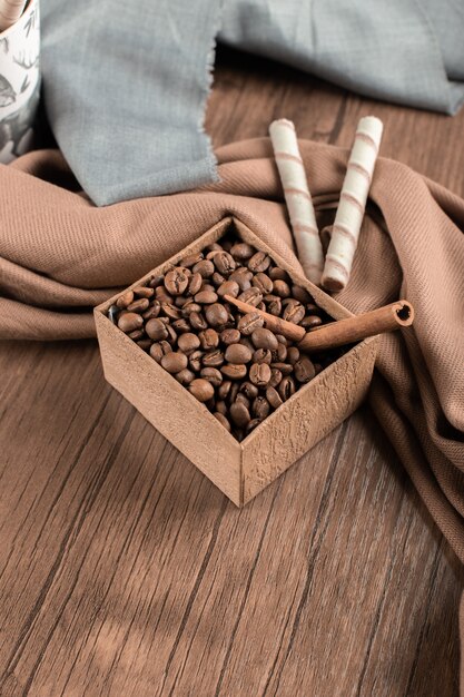 Кофе в зернах и корицы в коробке на деревянном столе