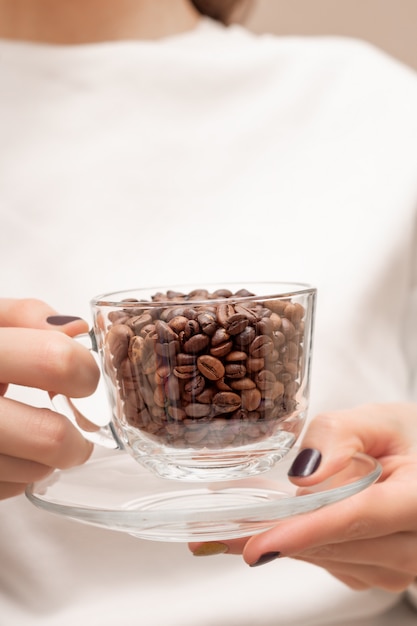 女性の手にガラスカップのコーヒー豆。