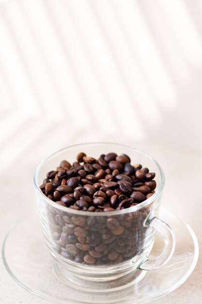 Coffee beans in a glass cup on a table.