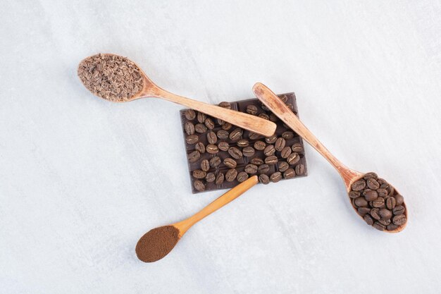 Coffee beans, ground coffee and cocoa powder on wooden spoons