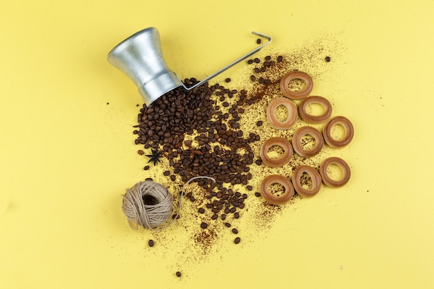 Coffee beans in a jug with rice cakes, ropes, buns flat lay on a yellow background