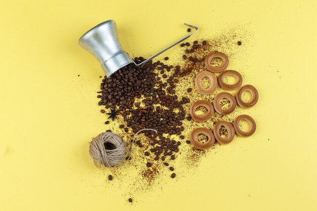 Coffee beans in a jug with rice cakes, ropes, buns flat lay on a yellow background