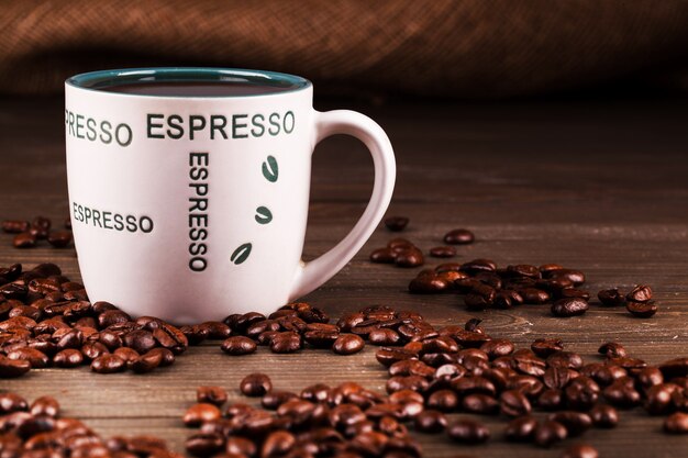 Кофейные бобы лежат вокруг чашки с эспрессо