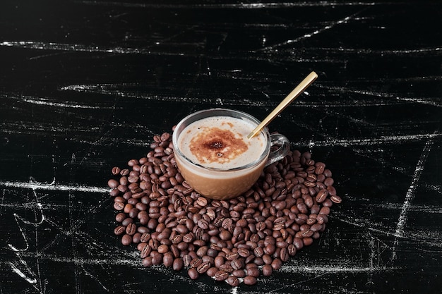 Бесплатное фото Кофейные зерна на черном фоне с чашкой напитка.