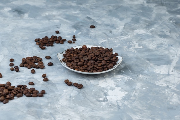 Coffee beans in a plate on a grey plaster background. high angle view.