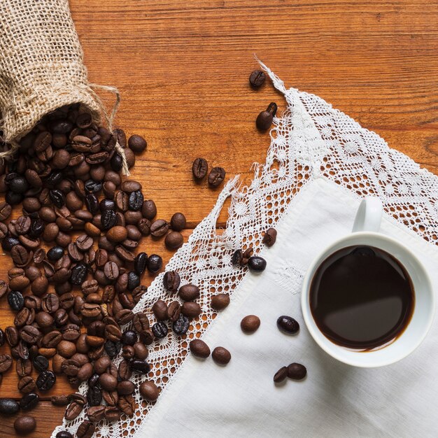 Coffee beans spilled near cup