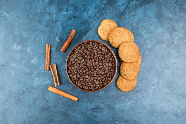 Foto gratuita chicchi di caffè con biscotti su sfondo blu scuro