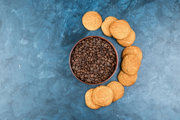 Coffee beans with biscuits on dark blue background