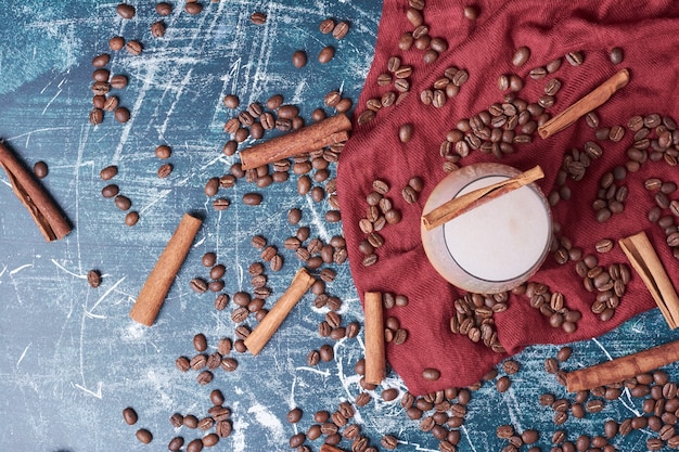 Coffee beans with a cup of drink on blue.