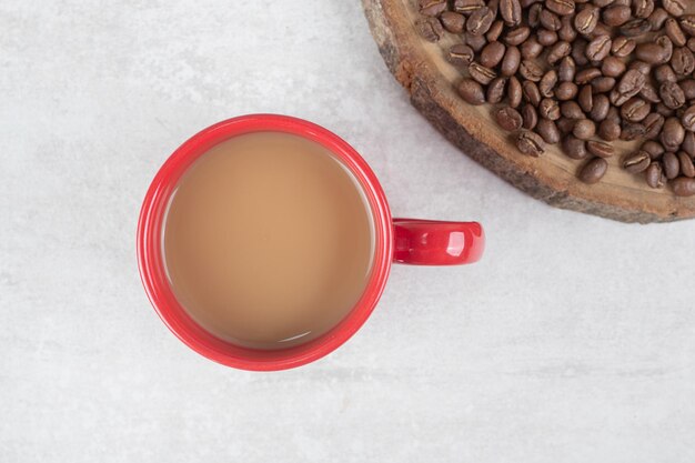 赤い一杯のコーヒーと木片のコーヒー豆