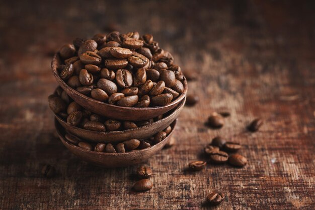 Coffee beans on wooden small bowls on old wooden vintage background. Closeup