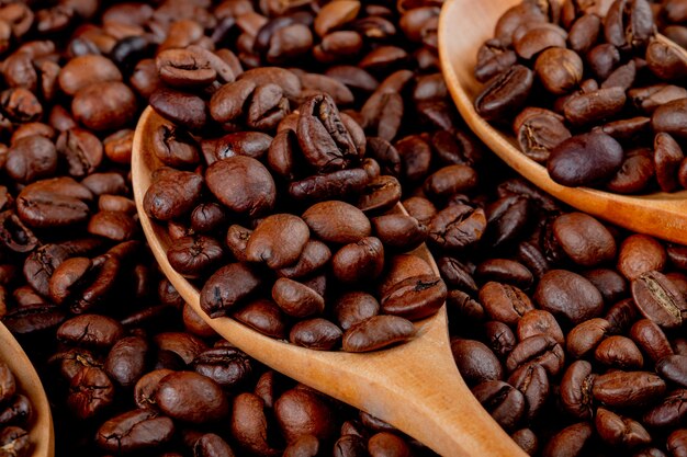 Coffee beans in a wooden spoon on coffee bean close up view