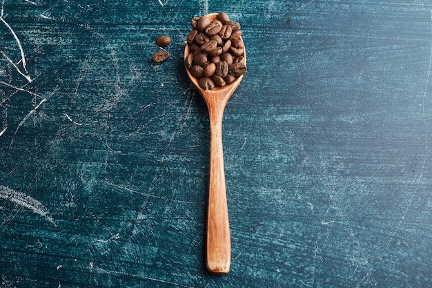 Chicchi di caffè in un cucchiaio di legno.
