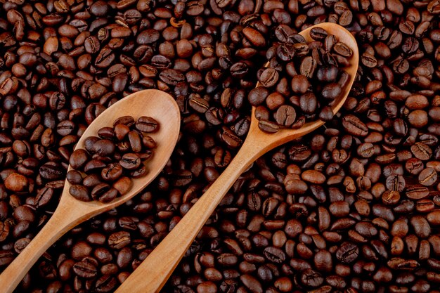 Coffee beans in wooden spoons on coffee beans top view background