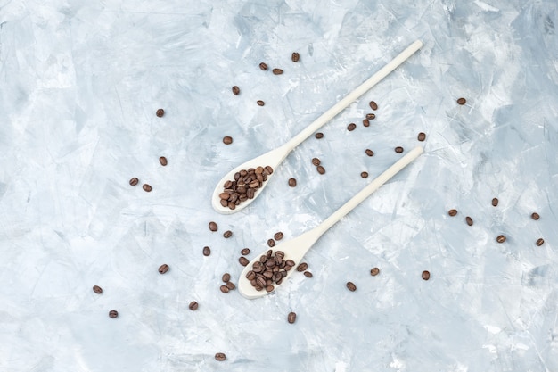 Coffee beans in wooden spoons flat lay on a grey plaster background