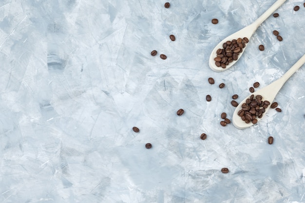 Coffee beans in wooden spoons flat lay on a grey plaster background