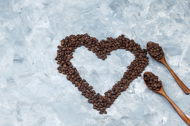 Coffee beans in wooden spoons flat lay on a grey plaster background