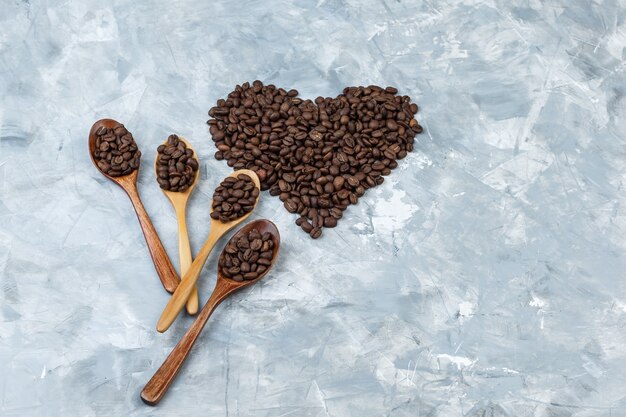 平らな木のスプーンのコーヒー豆は灰色の漆喰の背景に横たわっていた