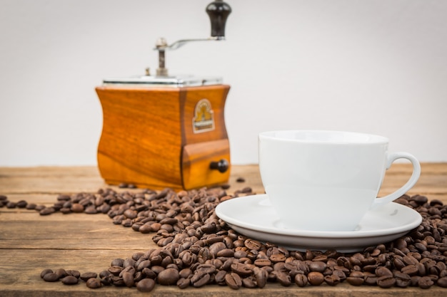 Coffee beans on a wooden table with a cup and a grinder