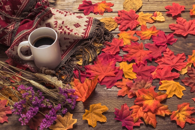 Coffee and blanket near leaves and flowers