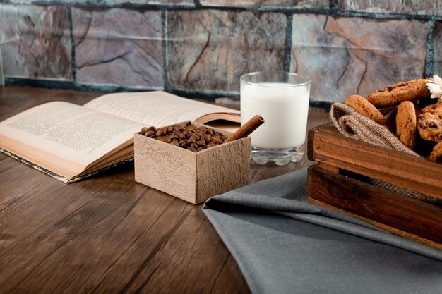 Coffee box, cookie tray, glass of milk and a book